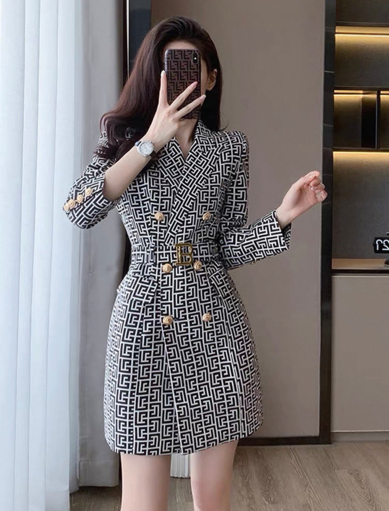 Woman wearing a patterned dress taking a mirror selfie.