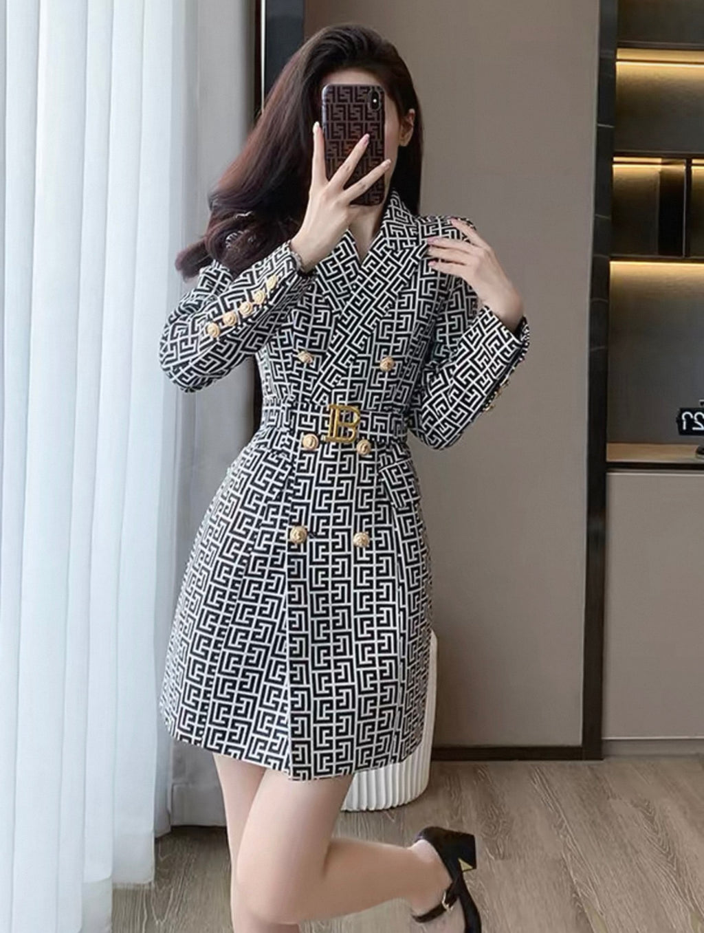 Woman taking a mirror selfie wearing a patterned dress indoors.
