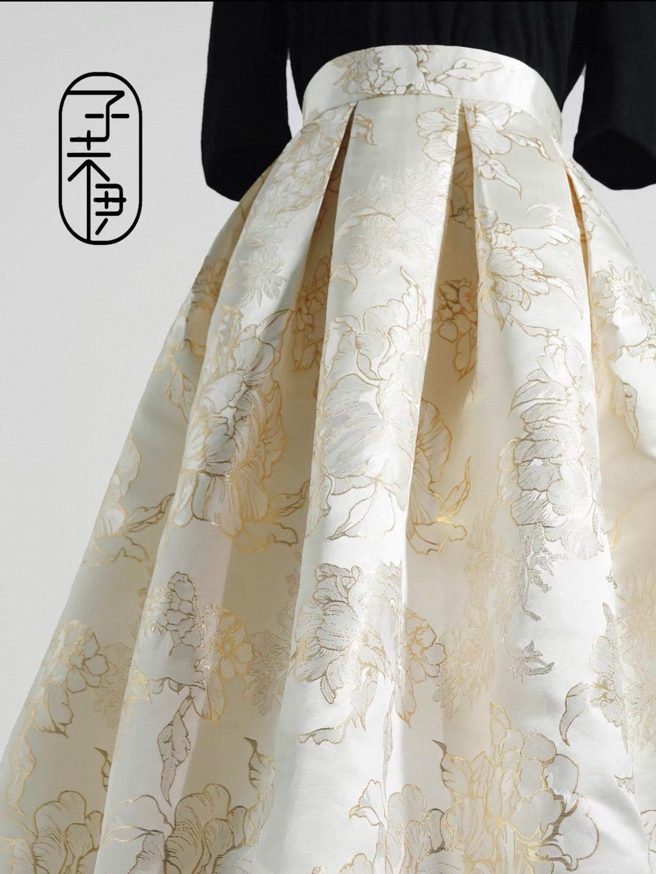 White pleated skirt with gold floral patterns on a white background