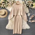 Beige sweater and pleated skirt set with shoes and hat on a decorative surface.