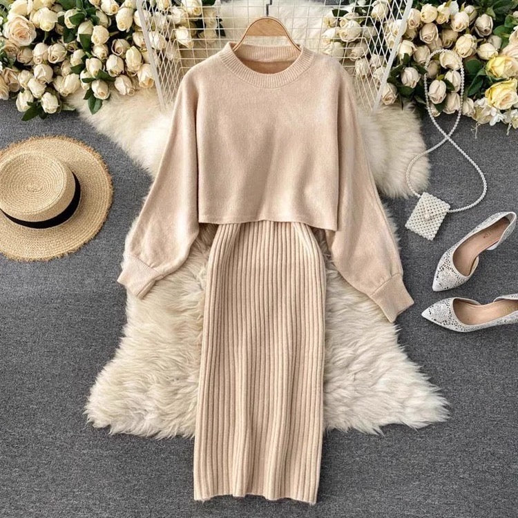Beige sweater and pleated skirt set with shoes and hat on a decorative surface.