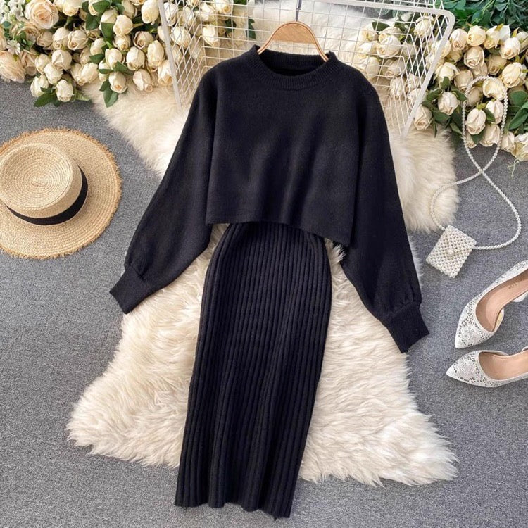 Black sweater and pleated skirt set on a white fur rug with decorative elements.
