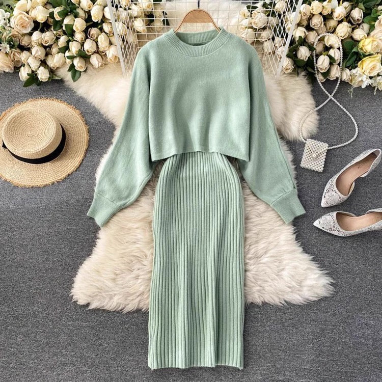 Green sweater and skirt set with accessories on a textured surface with floral decorations.