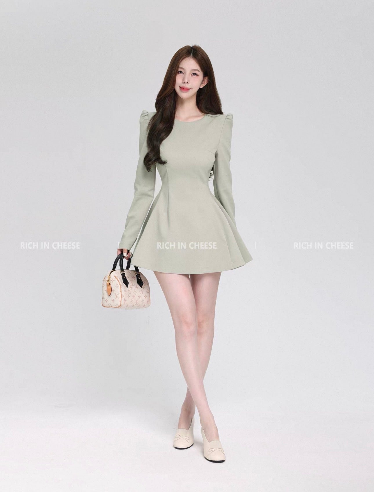Woman wearing a light green dress holding a handbag on a white background