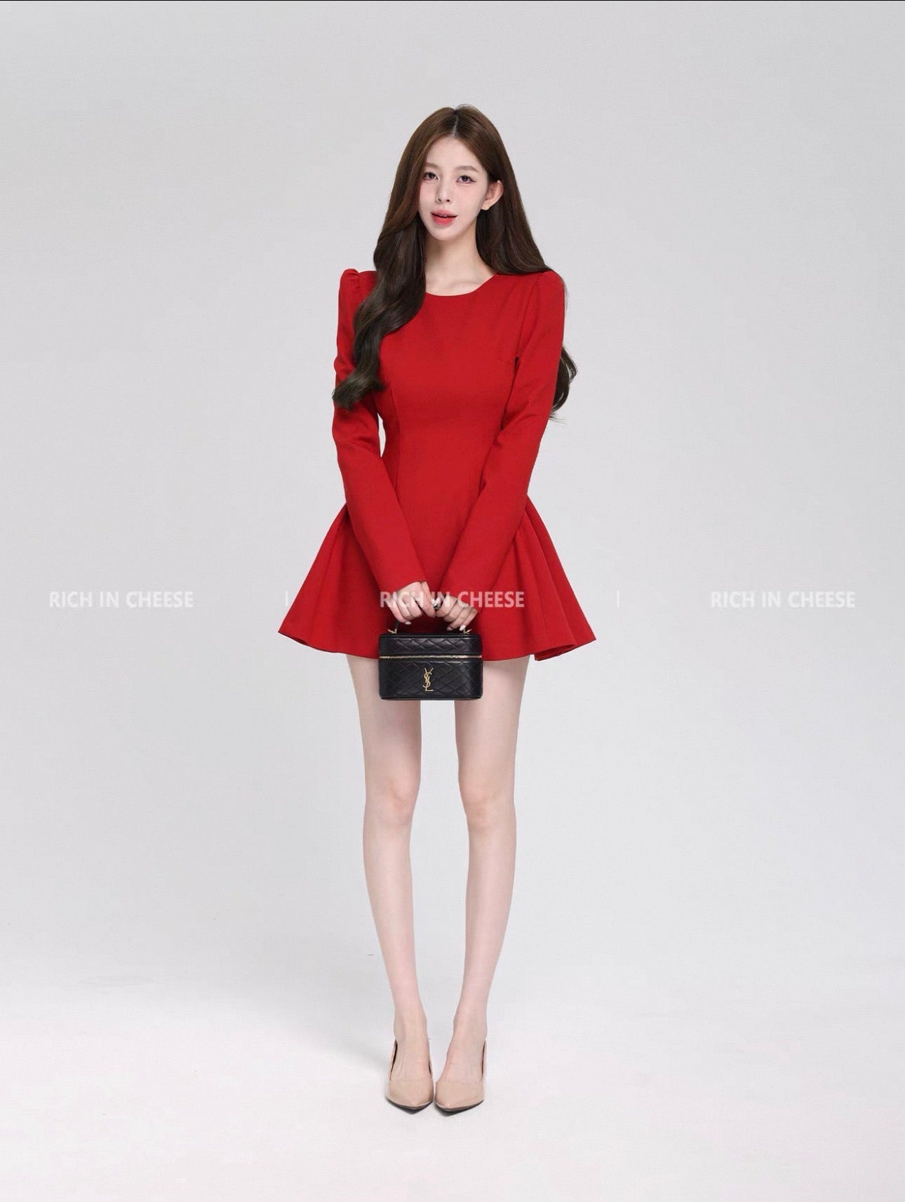 Woman wearing a red dress holding a black handbag on a white background