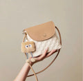 Small square crossbody bag in beige and white with woven texture and plush charm accessory.