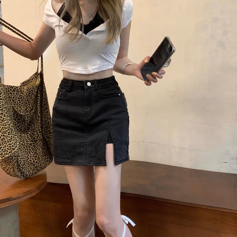 Person wearing a white crop top and black denim skirt holding a phone and leopard print bag.