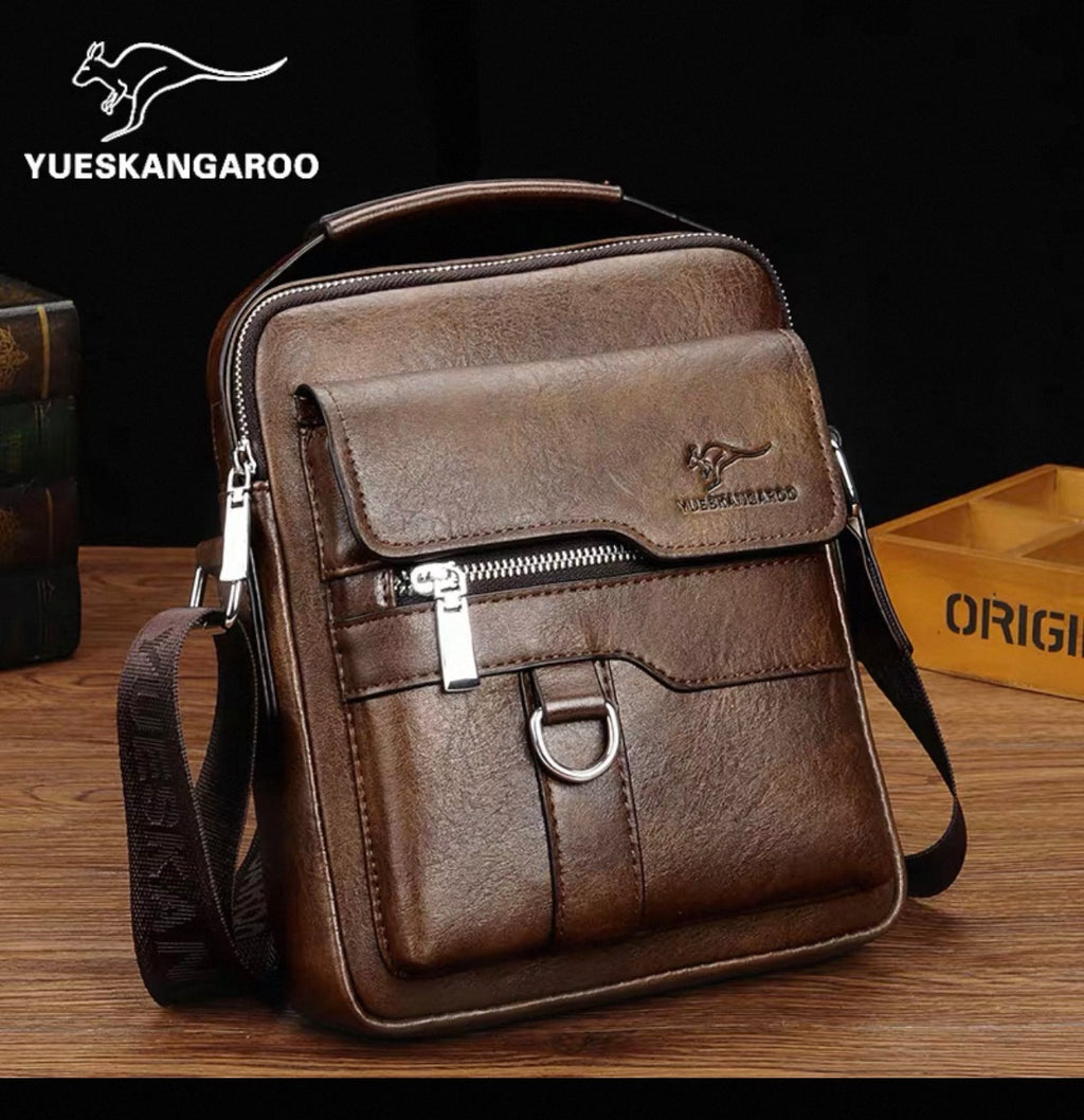 Brown leather crossbody bag with visible YUESKANGAROO branding on a wooden surface.
