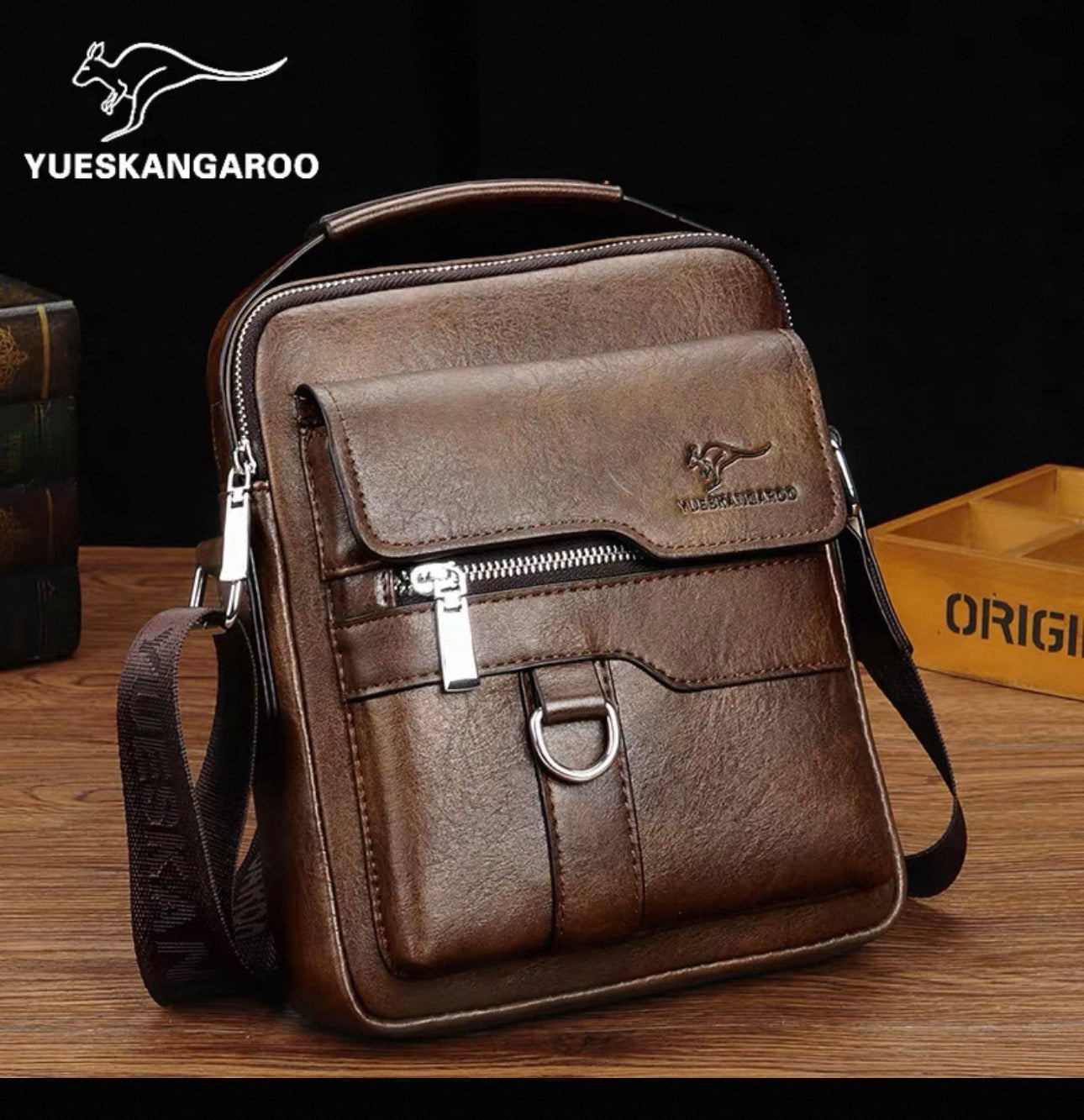 Brown leather crossbody bag with visible YUESKANGAROO branding on a wooden surface.