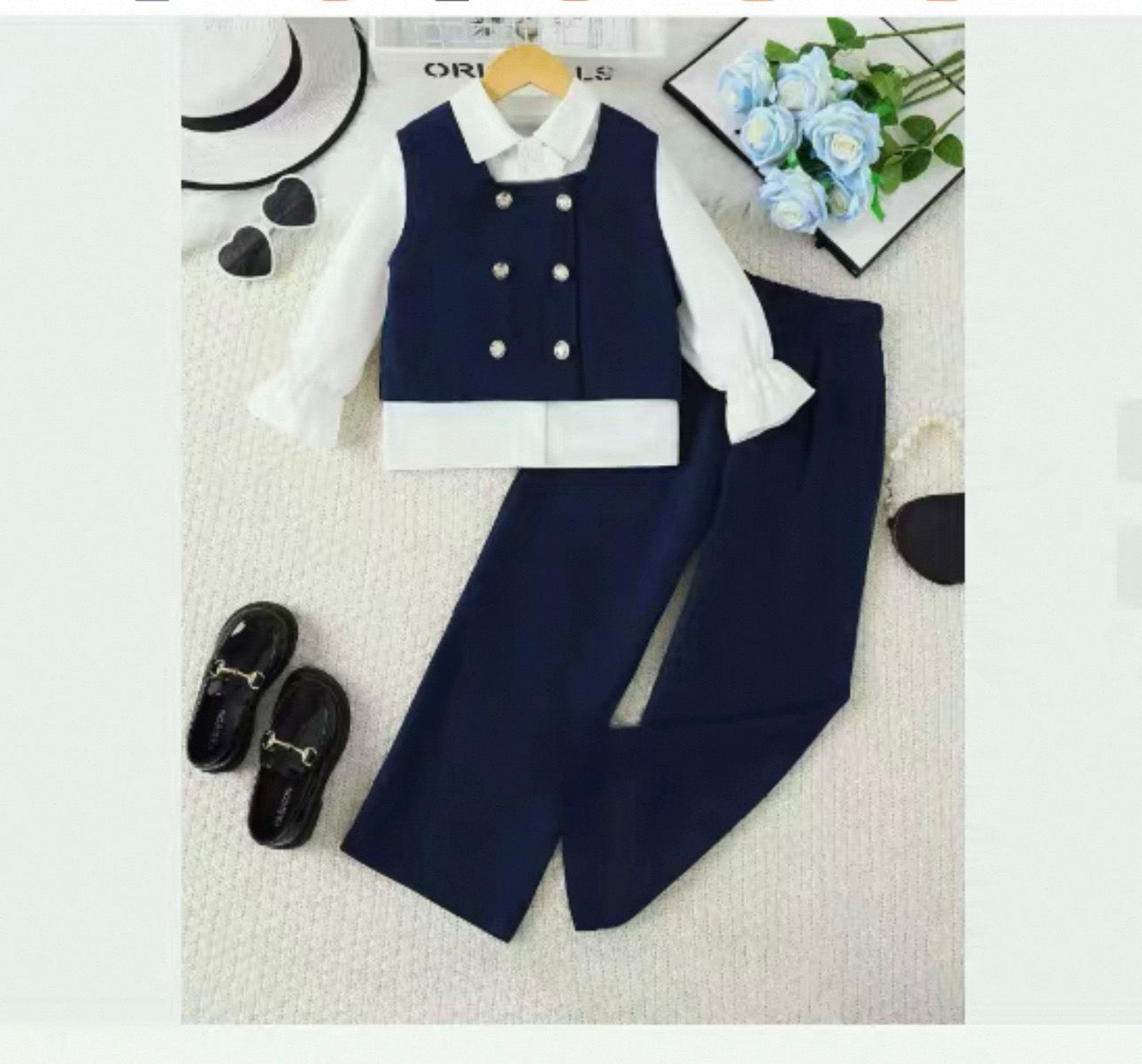 Children's navy vest and pants set with white shirt on a light gray background.