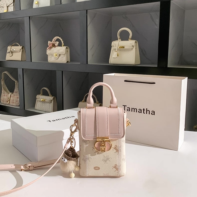 Pink handbag with gold accents on a white surface, with 'Tamatha' branding visible.