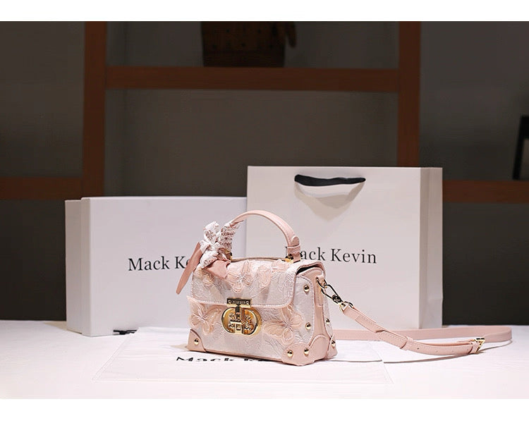 Pink handbag with decorative elements on a white surface with 'Mack Kevin' branding.