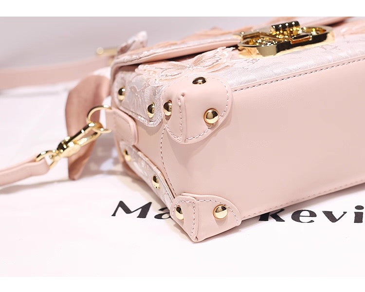 Pink handbag with gold accents on a white surface