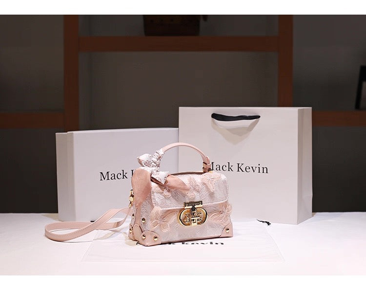 Pink handbag with gold accents on a white surface next to a branded box.