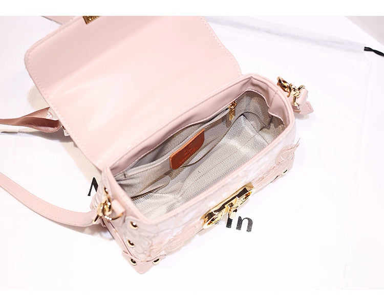 Pink handbag with gold accents on a white background