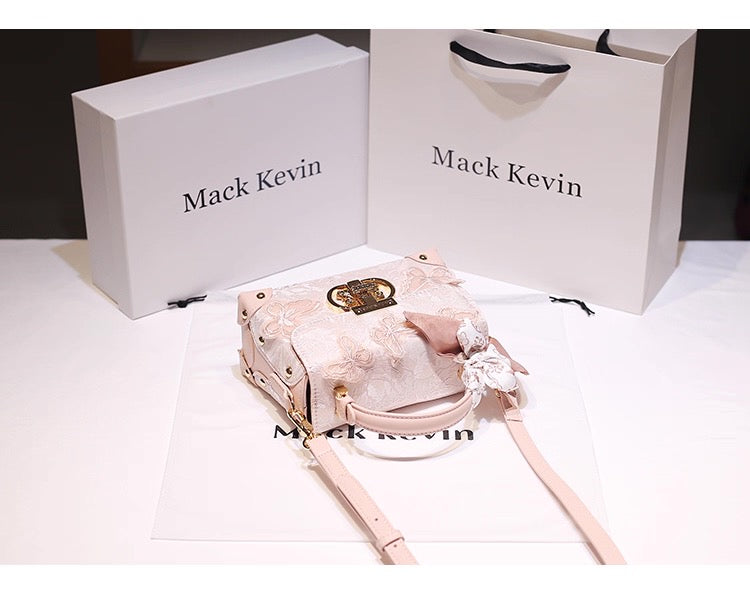 Pink handbag with floral details on a white surface, with 'Mack Kevin' branding.