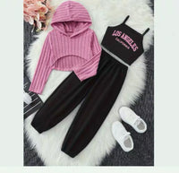 Pink hoodie, black tank top with 'Los Angeles California' text, black pants, and white sneakers on a textured surface.