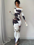 Woman wearing a long, off-shoulder dress with abstract pattern in a room with gray curtains.