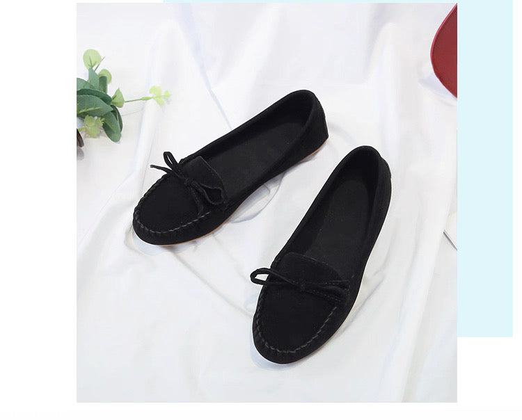Pair of black loafers on a white fabric background