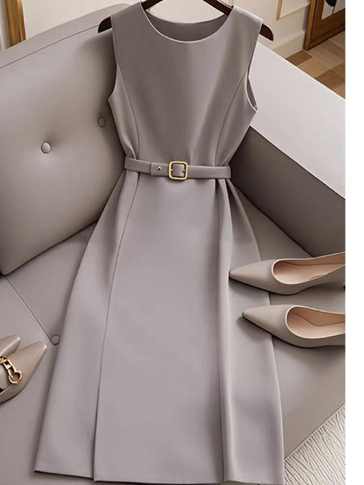 Gray dress with a belt on a hanger, surrounded by shoes on a light gray surface.