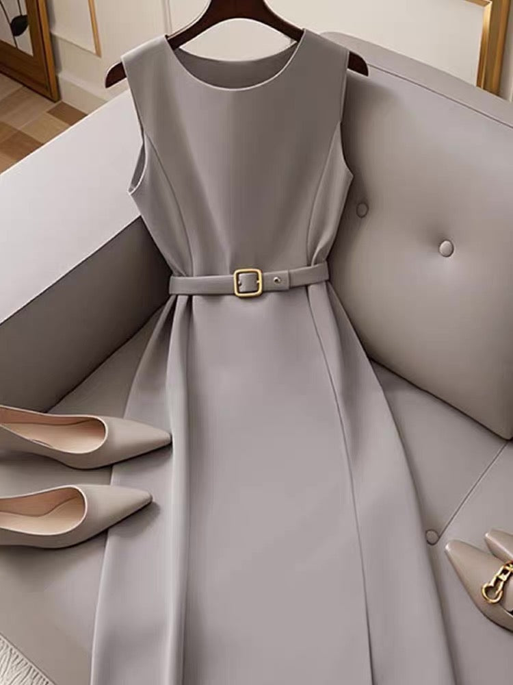 Gray dress with a belt on a hanger, paired with beige shoes on a gray couch.