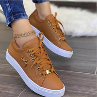 Brown sneakers with gold accents worn by a person on a wooden floor.