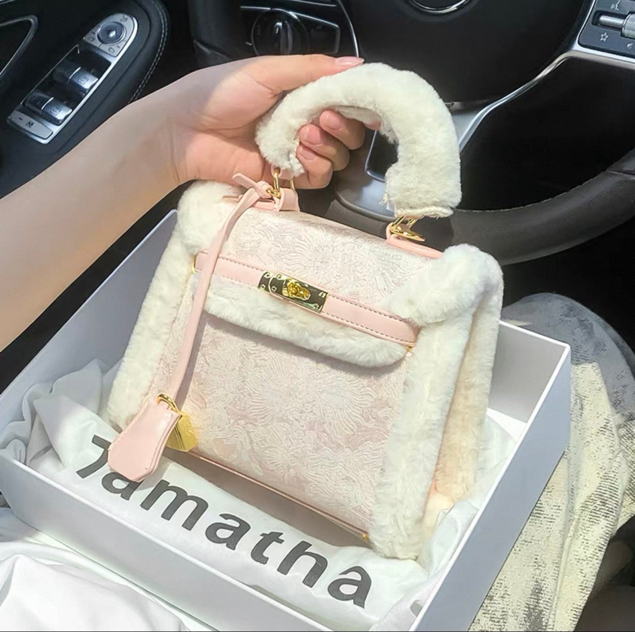 Pink embroidered Kelly-style bag with gold clasp, fluffy white faux fur trim, and top handle attached to a crossbody strap.