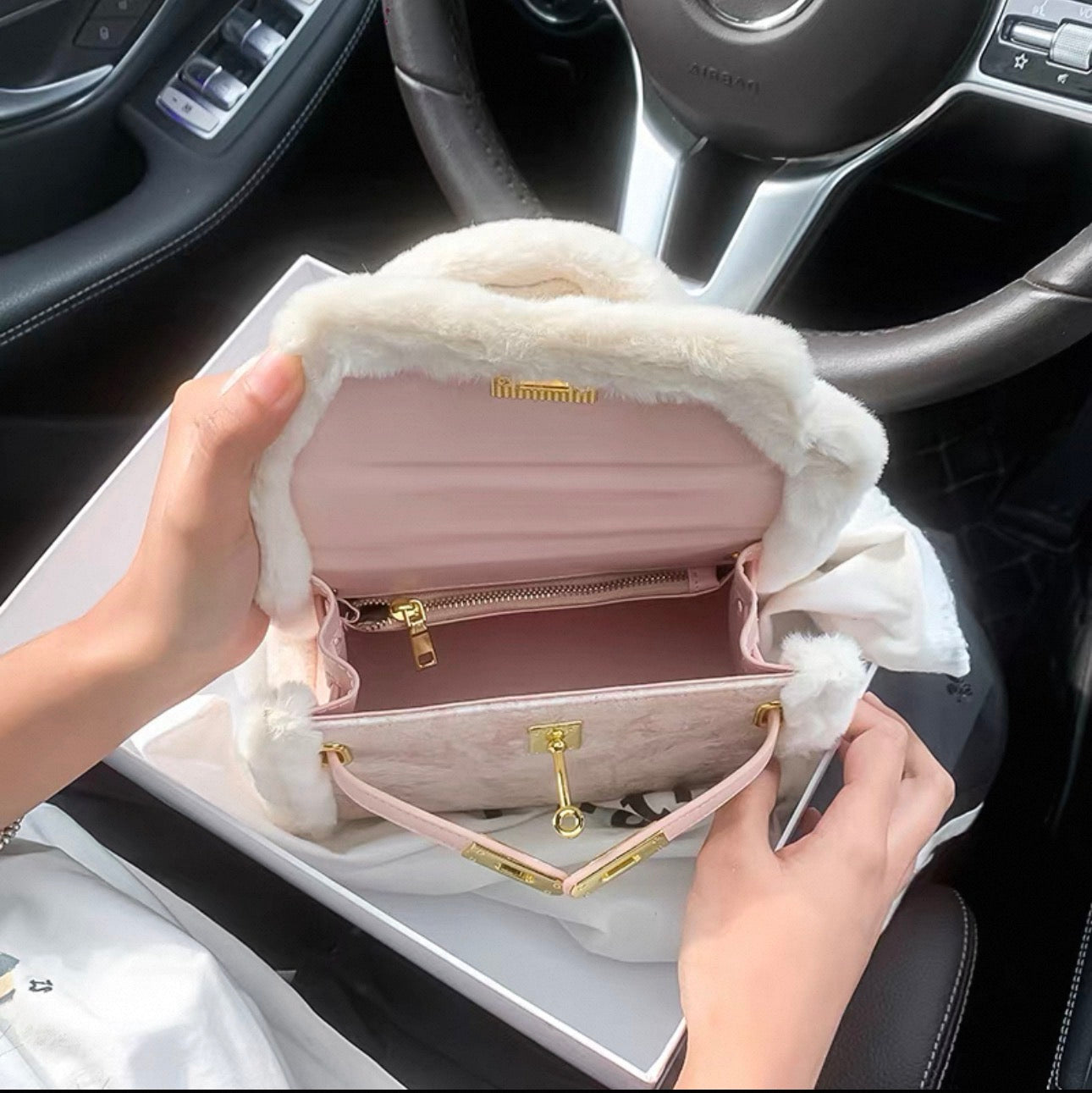 Pink leather Kelly-style bag with gold hardware and soft white fur trim, open interior showing zippered and compartmental.