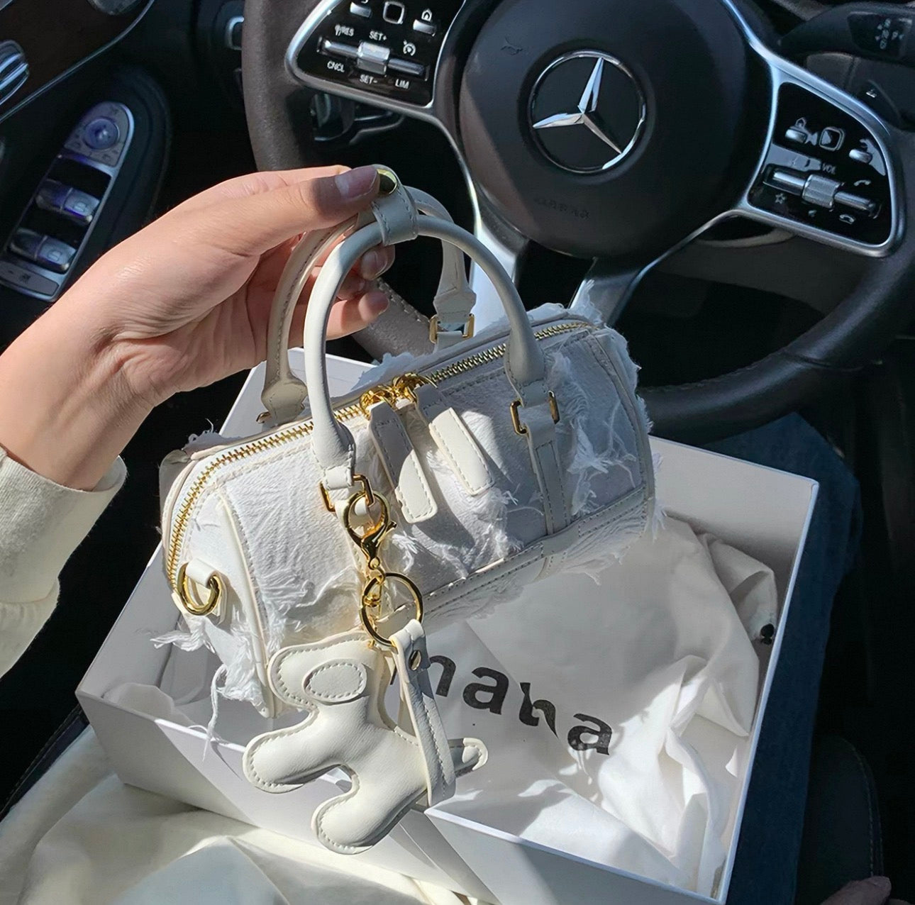 White Boston handbag with raised snowflake patterns and teddy bear tassel charm.