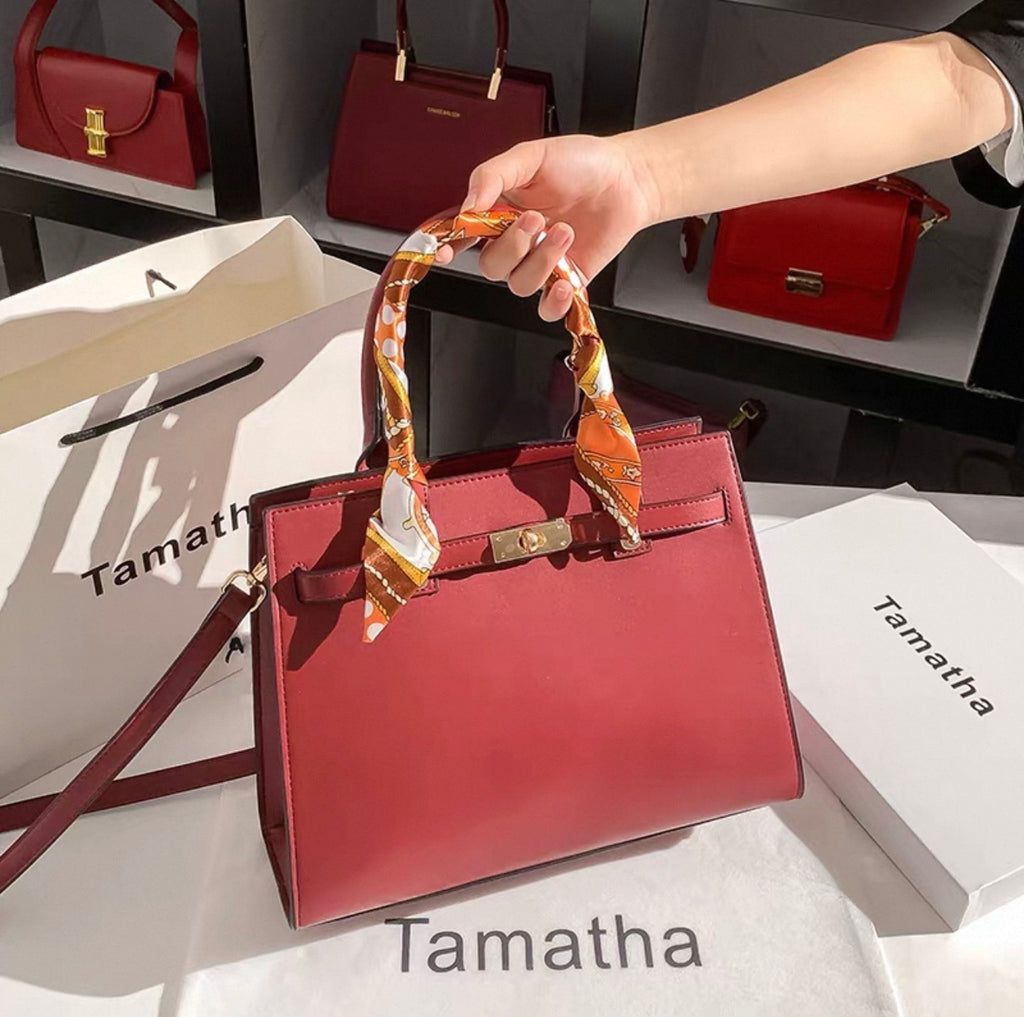 Red Kelly-style handbag with structured shape, gold-tone hardware, and silk scarf wrapped handle.