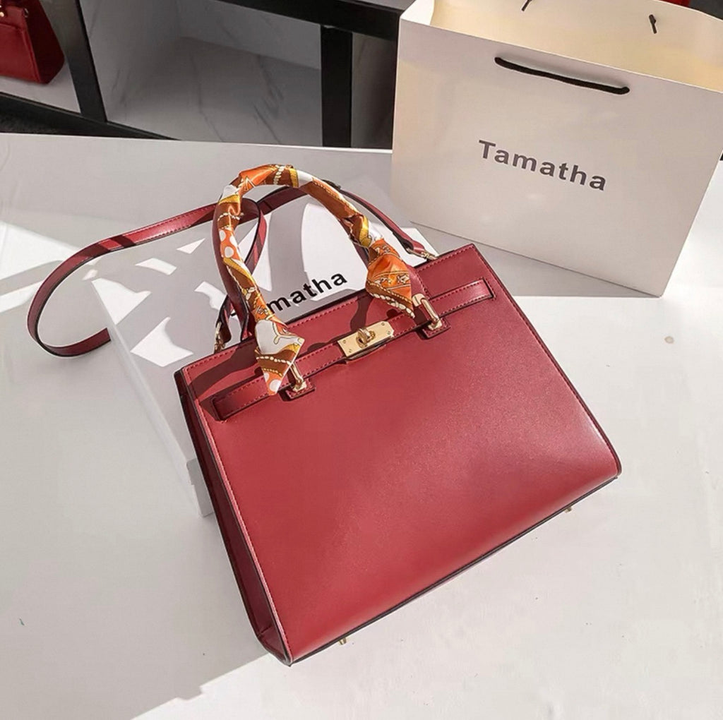 Red Kelly-style handbag with gold hardware and silk scarf wrapped handle.