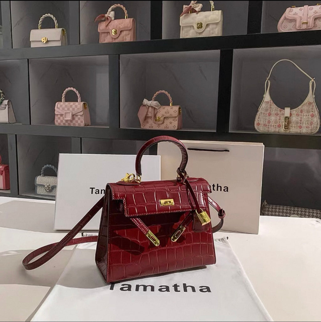 Ruby red stone-patterned bridal handbag with gold lock and top handle.