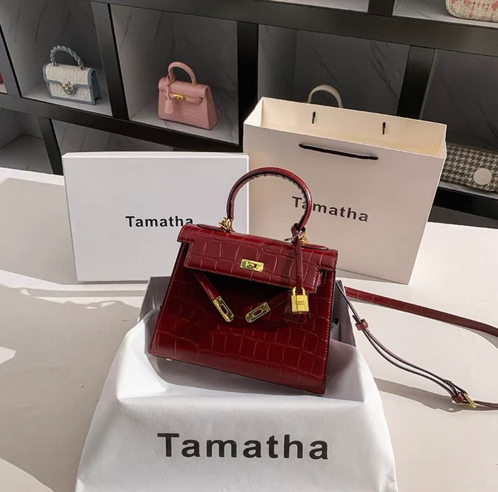 Ruby red Kelly-style handbag with crocodile texture, gold lock, and detachable strap.