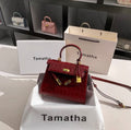 Ruby red Kelly-style handbag with crocodile texture, gold lock, and detachable strap.