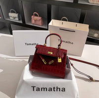 Ruby red Kelly-style handbag with crocodile texture, gold lock, and detachable strap.