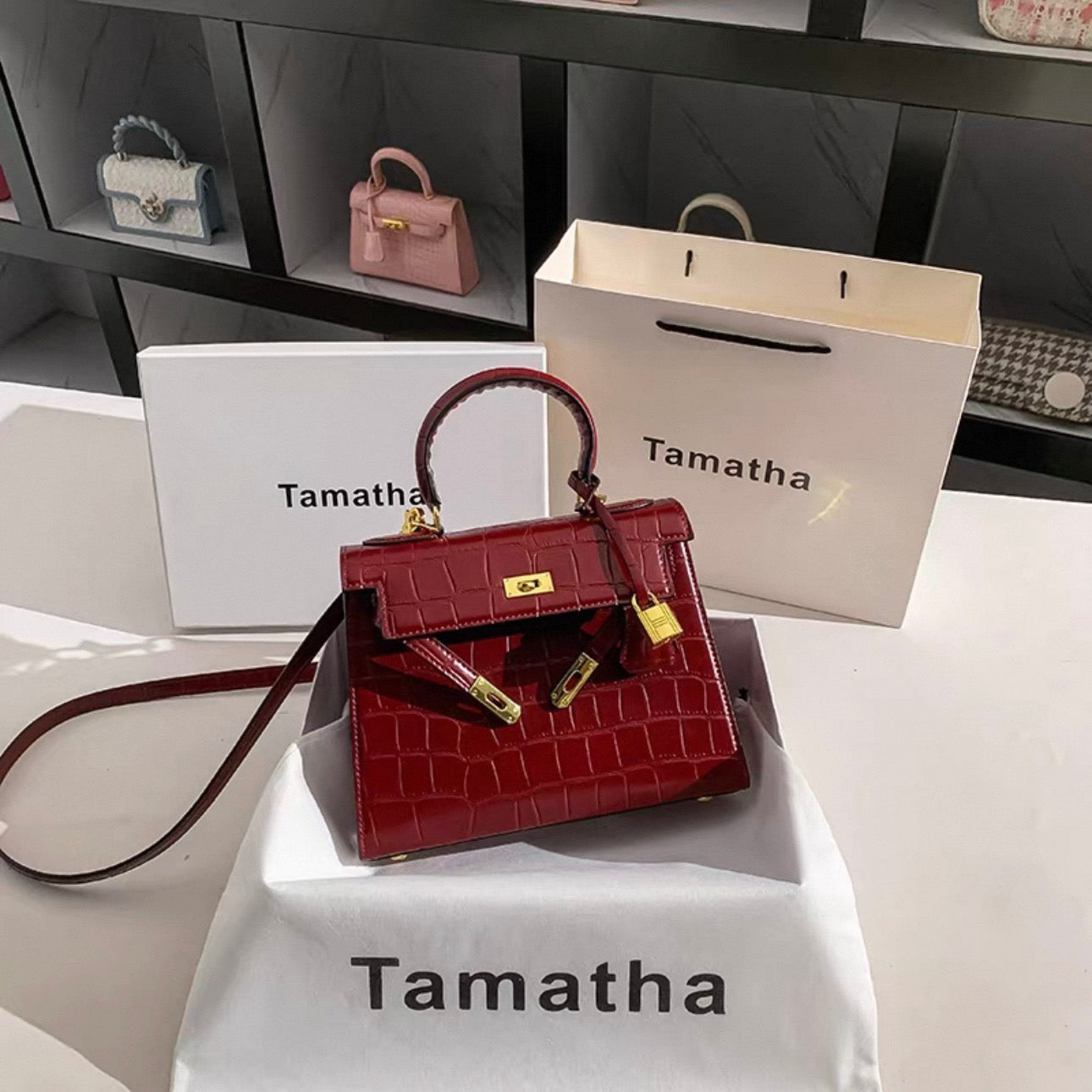 Ruby red Kelly-style handbag with glossy stone-pattern texture and gold lock hardware.