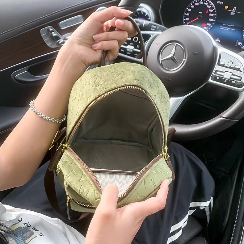 Person holding a green textured bag inside a car with a Mercedes-Benz steering wheel.