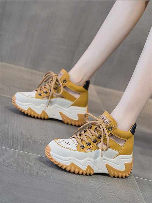 Yellow and white sneakers worn on a gray floor
