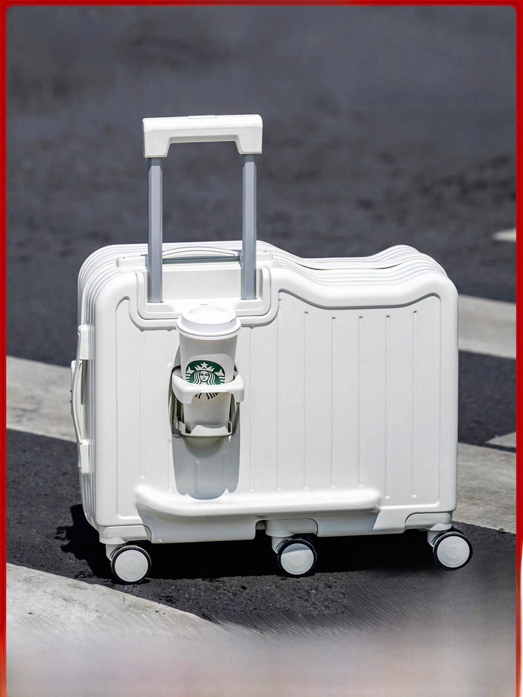 White suitcase with a Starbucks cup attached on a road.