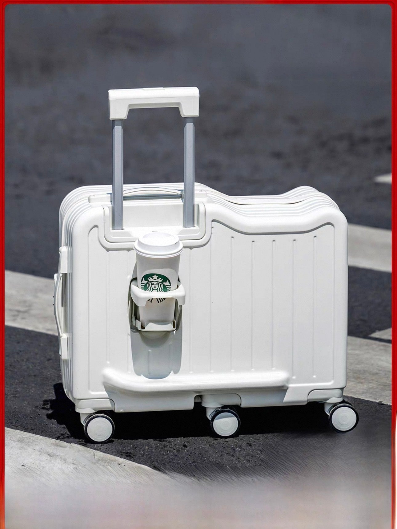 White suitcase with a Starbucks cup attached on a road.