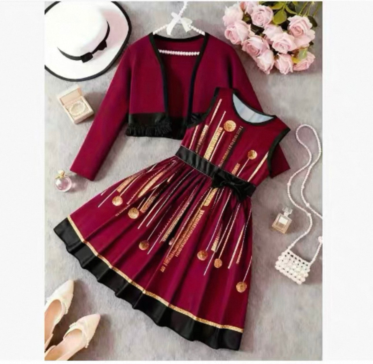 Red dress with gold accents on a gray surface with accessories.