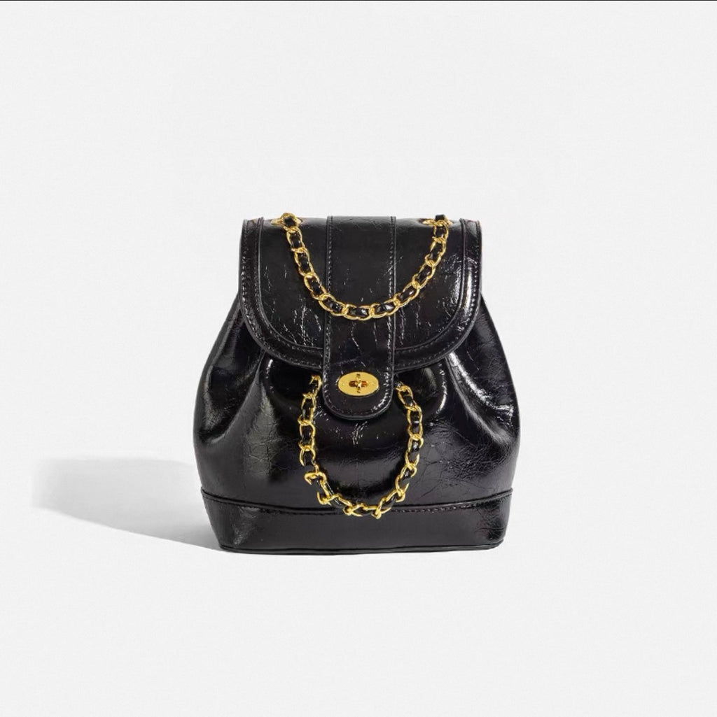 Black leather backpack with gold chain details on a white background
