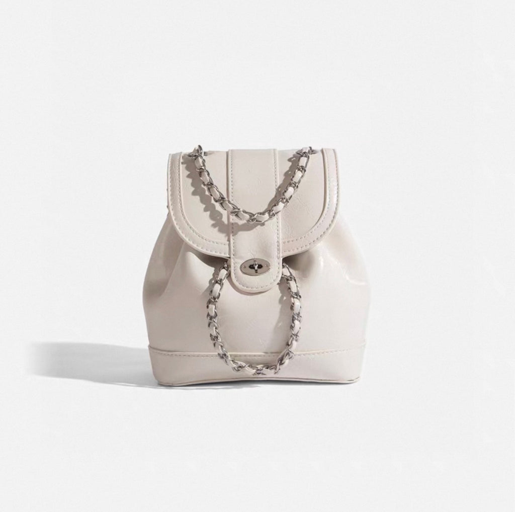 White backpack with chain details on a light gray background