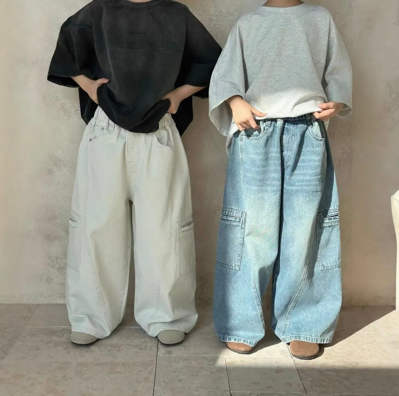 Two people wearing wide-leg pants against a plain background