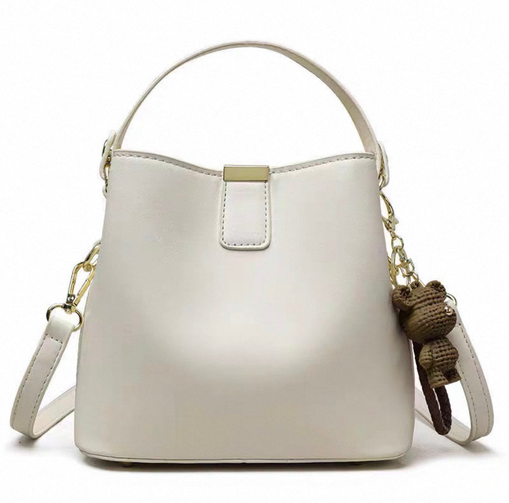 Beige leather bucket handbag with single handle, gold hardware, and detachable crossbody strap.