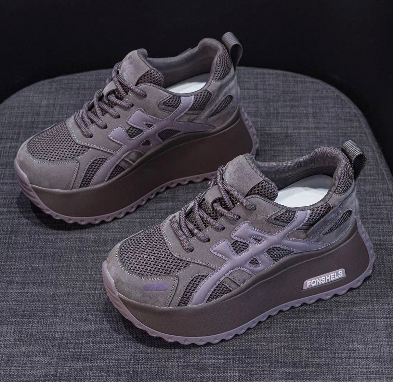 Gray sneakers with a brand logo on a textured surface