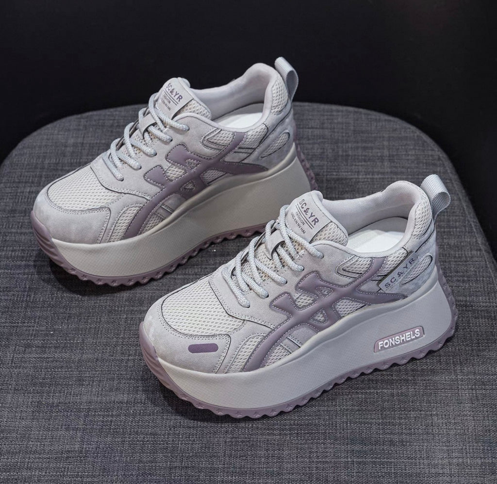Pair of gray sneakers on a textured surface with a dark background