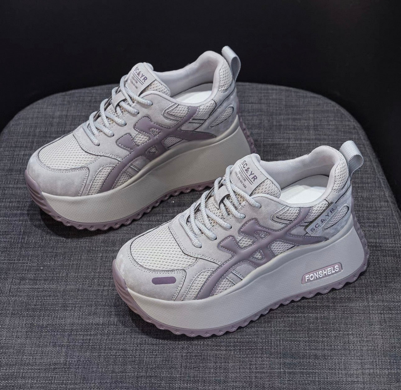Pair of gray sneakers on a textured surface with a dark background