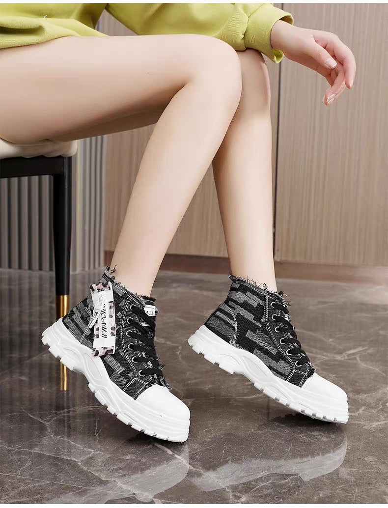Person wearing black and white sneakers with a brand tag, sitting on a chair.