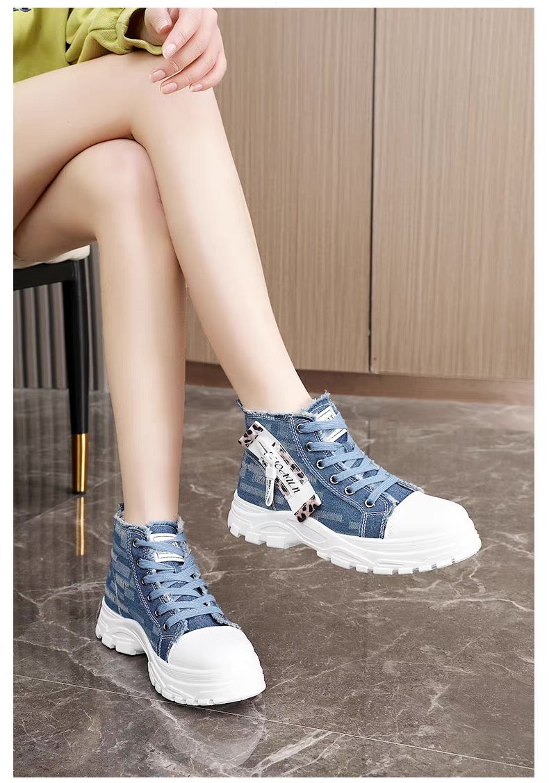 Person wearing blue denim high-top sneakers with white soles on a marble floor.